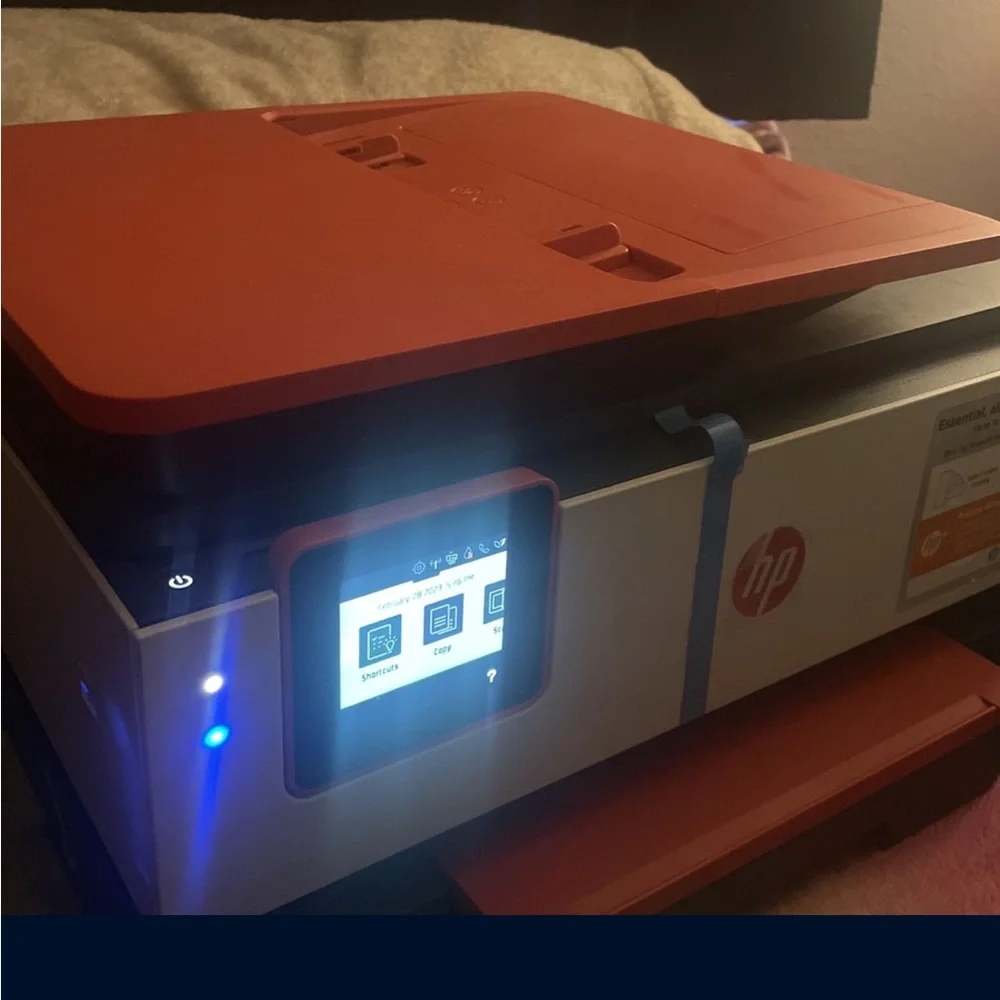 Red and white HP Printer . It’s brand new comes with paper and everything .